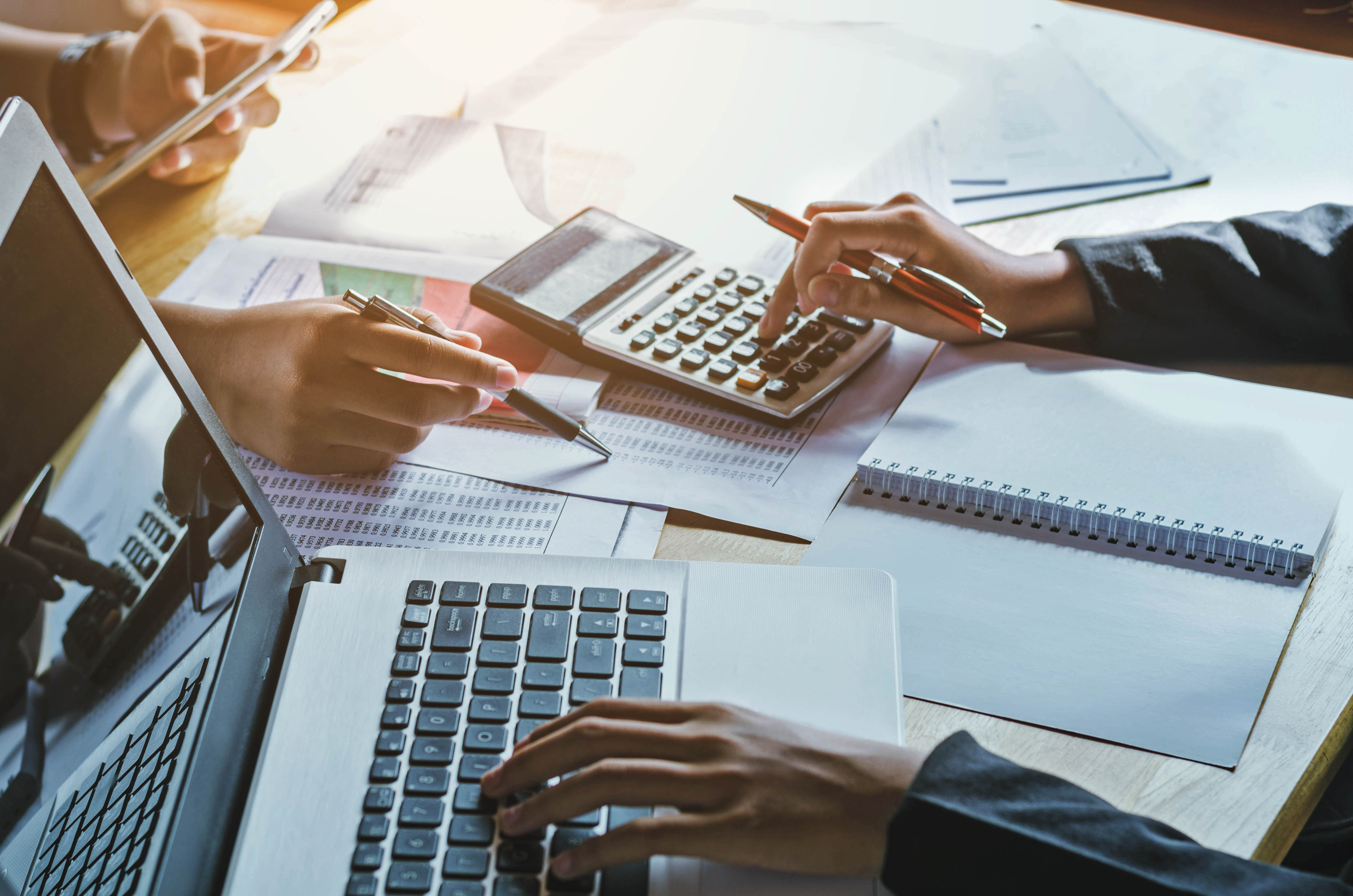 woman working on laptop and calculator reviewing electronic invoices